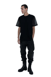 Person wearing a black t-shirt, black pants, and black boots on a white background